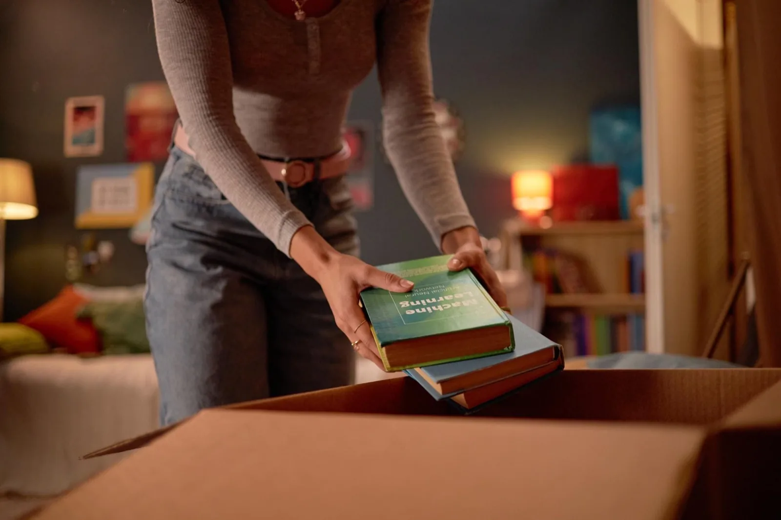 Hände verpacken einen Stapel gebrauchter Bücher in einen stabilen Karton zum Versand an Studibuch
