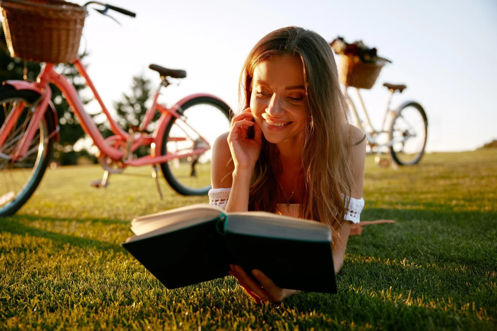 Junge Frau sitzt draußen auf einer Bank im Park und liest entspannt in einem Buch — Sinnbild für gebrauchte Bücher, die ein zweites Leben bekommen